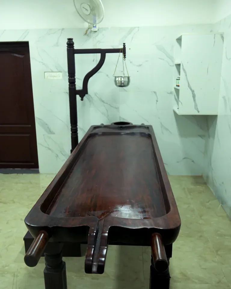 Ayurveda treatment room with a wooden treatment table at the Coimbatore clinic